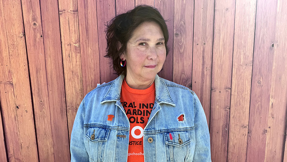 Photo of Dr. Dena Ned wearing an orange shirt and a denim jacket with an orange shirt-shaped pin